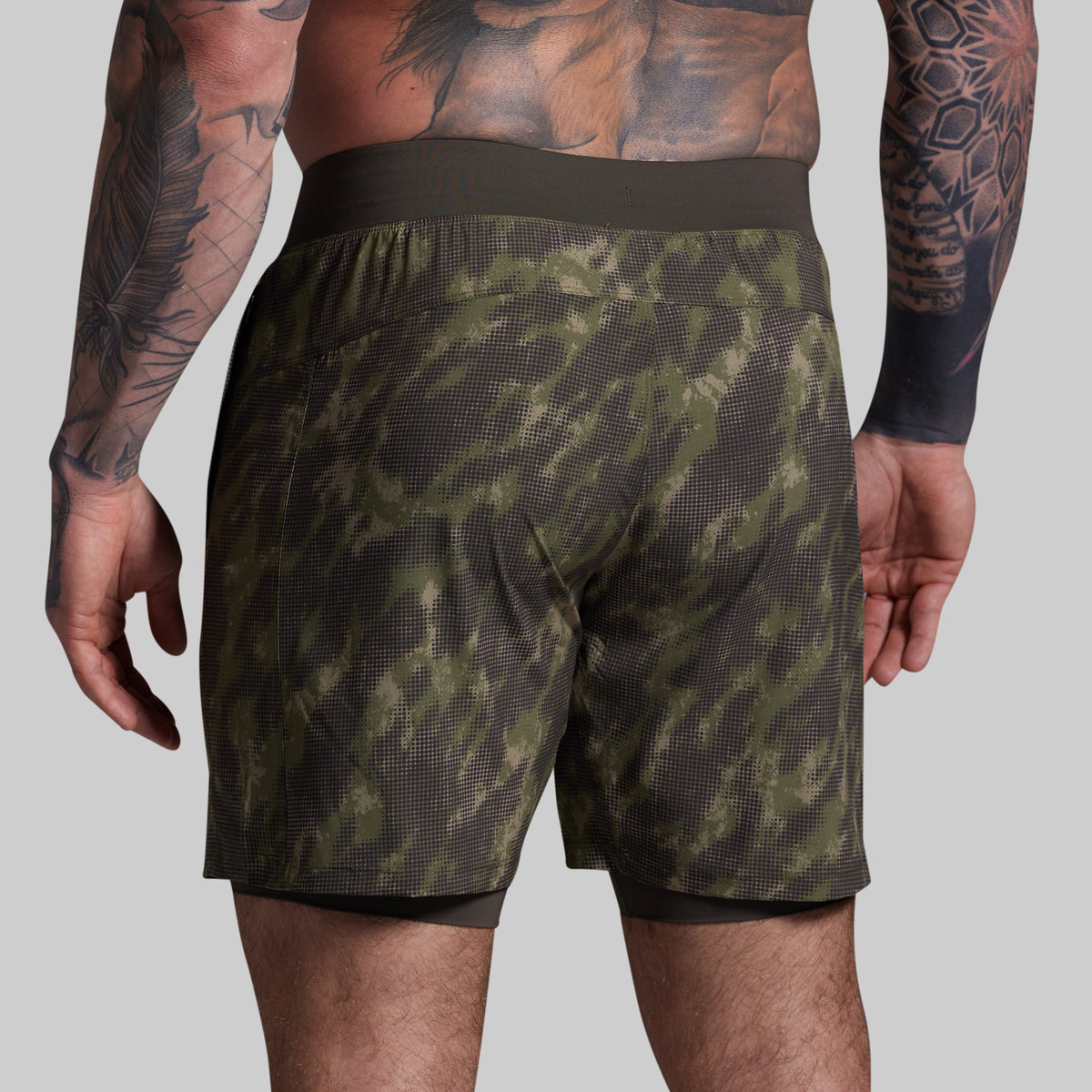 Person wearing green camouflage shorts on a gray background