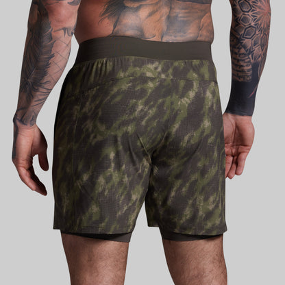 Person wearing green camouflage shorts on a gray background