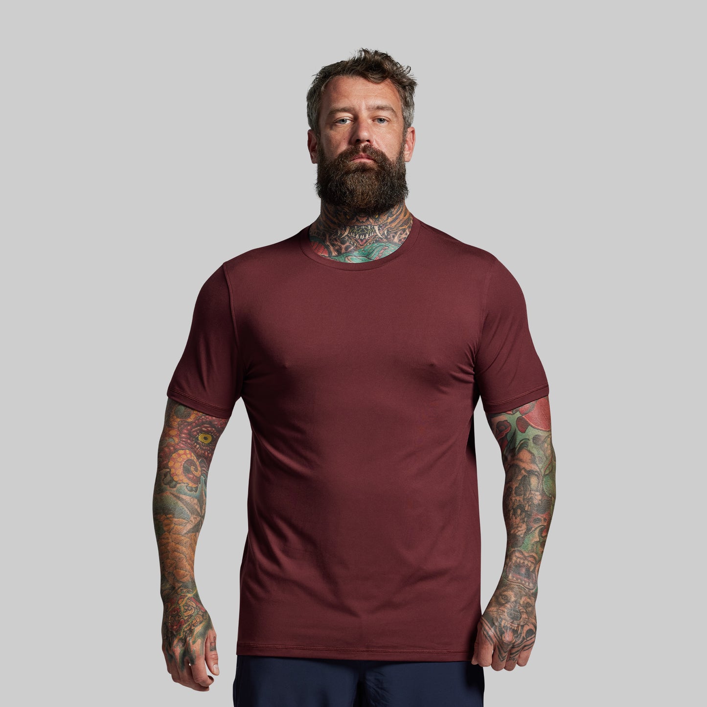 Man wearing a maroon t-shirt against a gray background