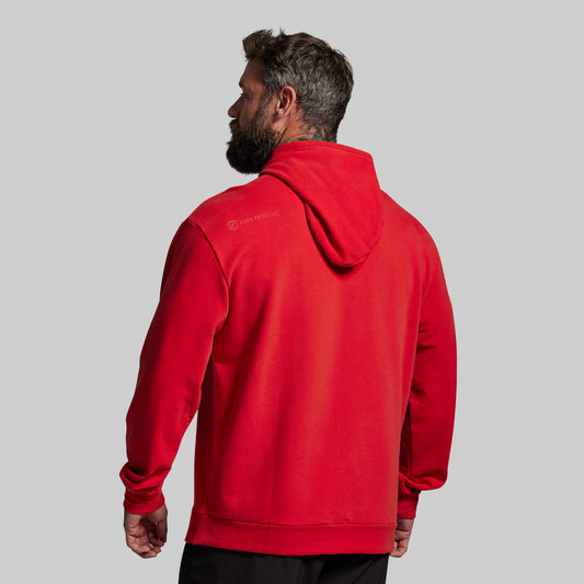 Man wearing a red hoodie with a brand logo on the back against a gray background