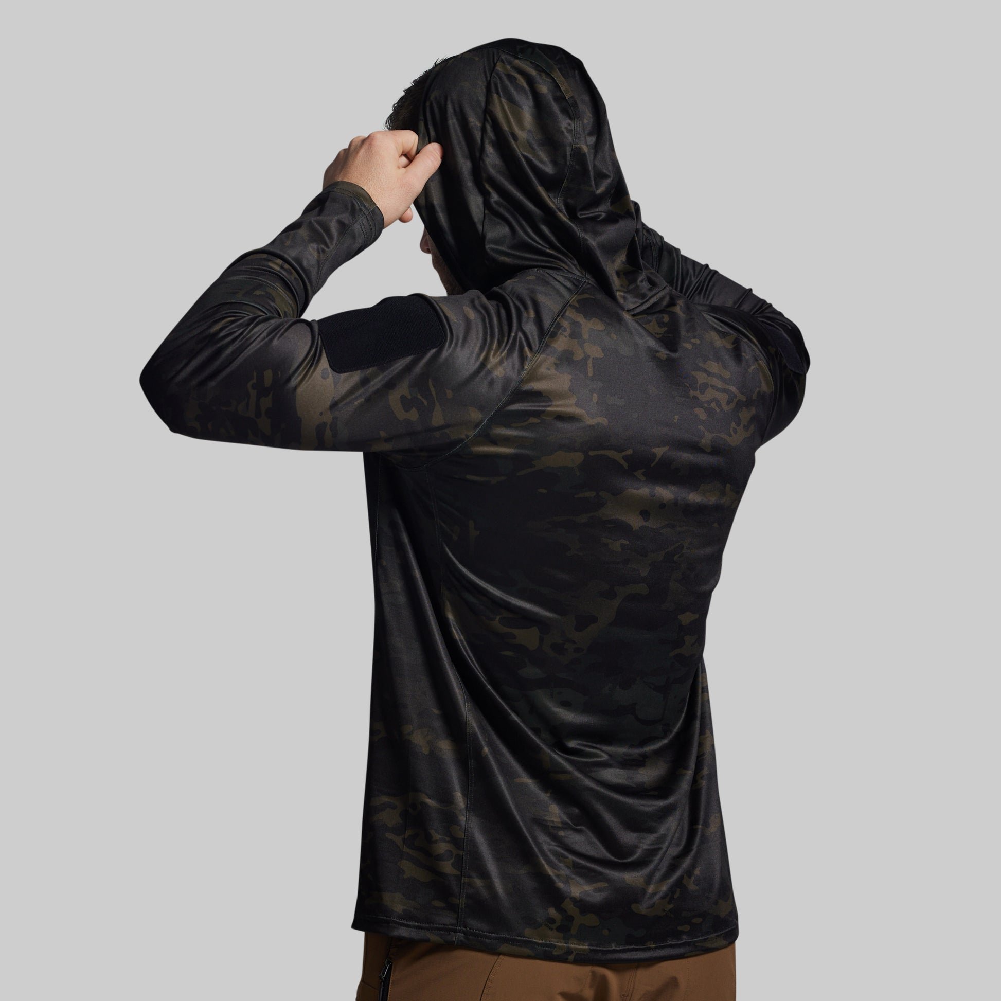Person wearing a black camouflage hoodie on a gray background