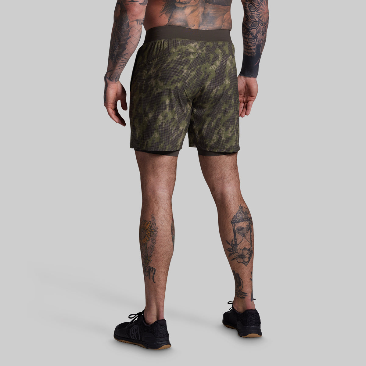 Person wearing camouflage shorts on a plain background