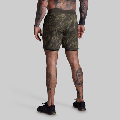 Person wearing camouflage shorts on a plain background