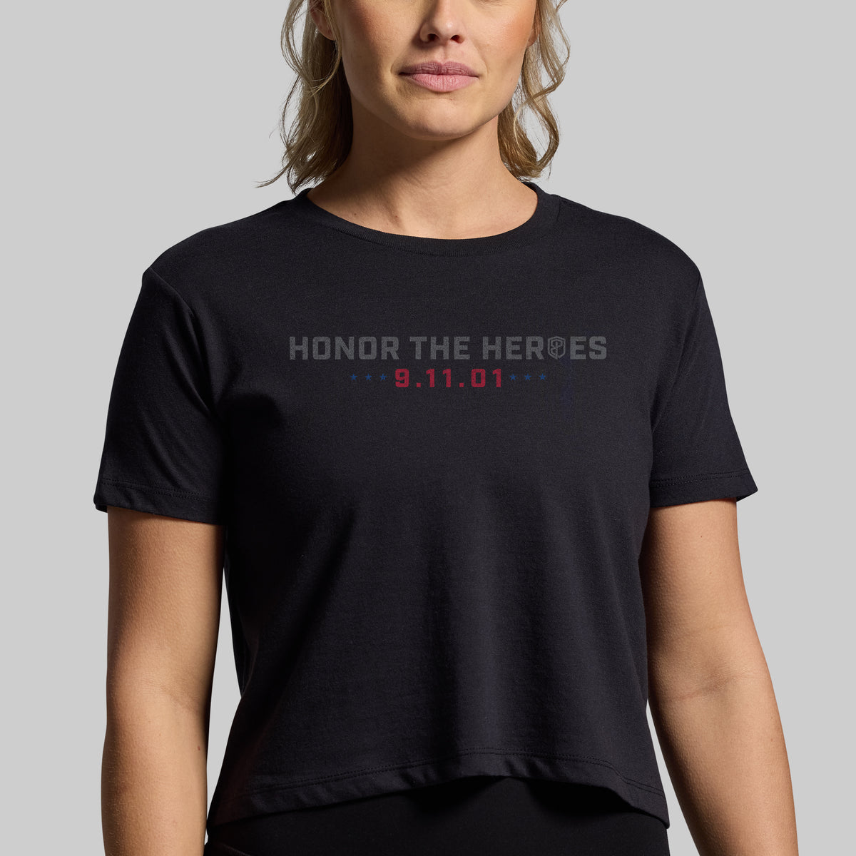 Woman wearing a black 9/11 25th Anniversary crop tee, front with Honor the Heroes and 9.11.01 graphic