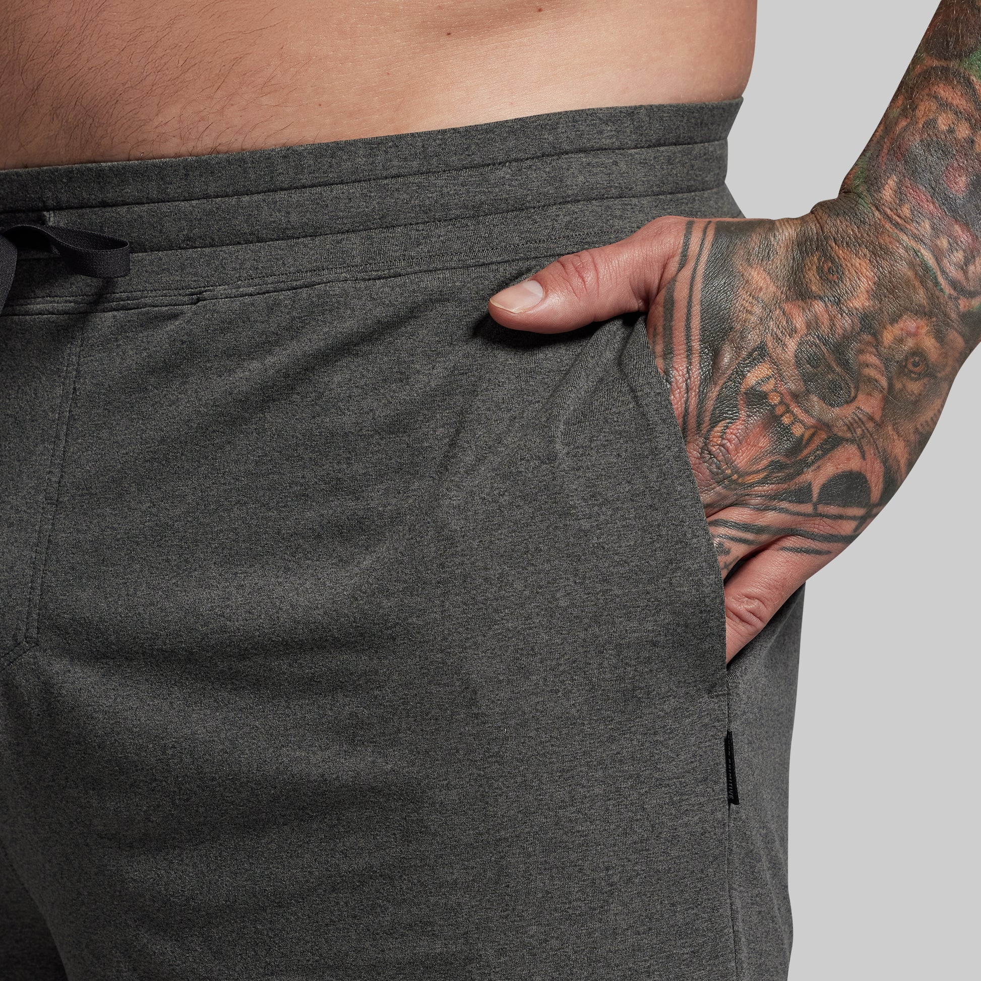 Person wearing dark gray athletic shorts with a tattooed arm visible.
