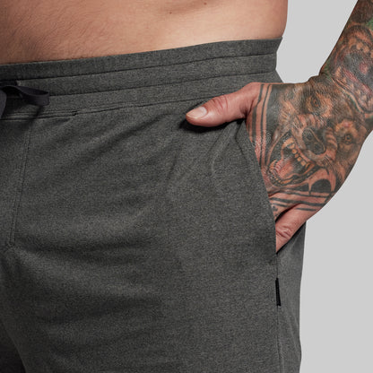 Person wearing dark gray athletic shorts with a tattooed arm visible.