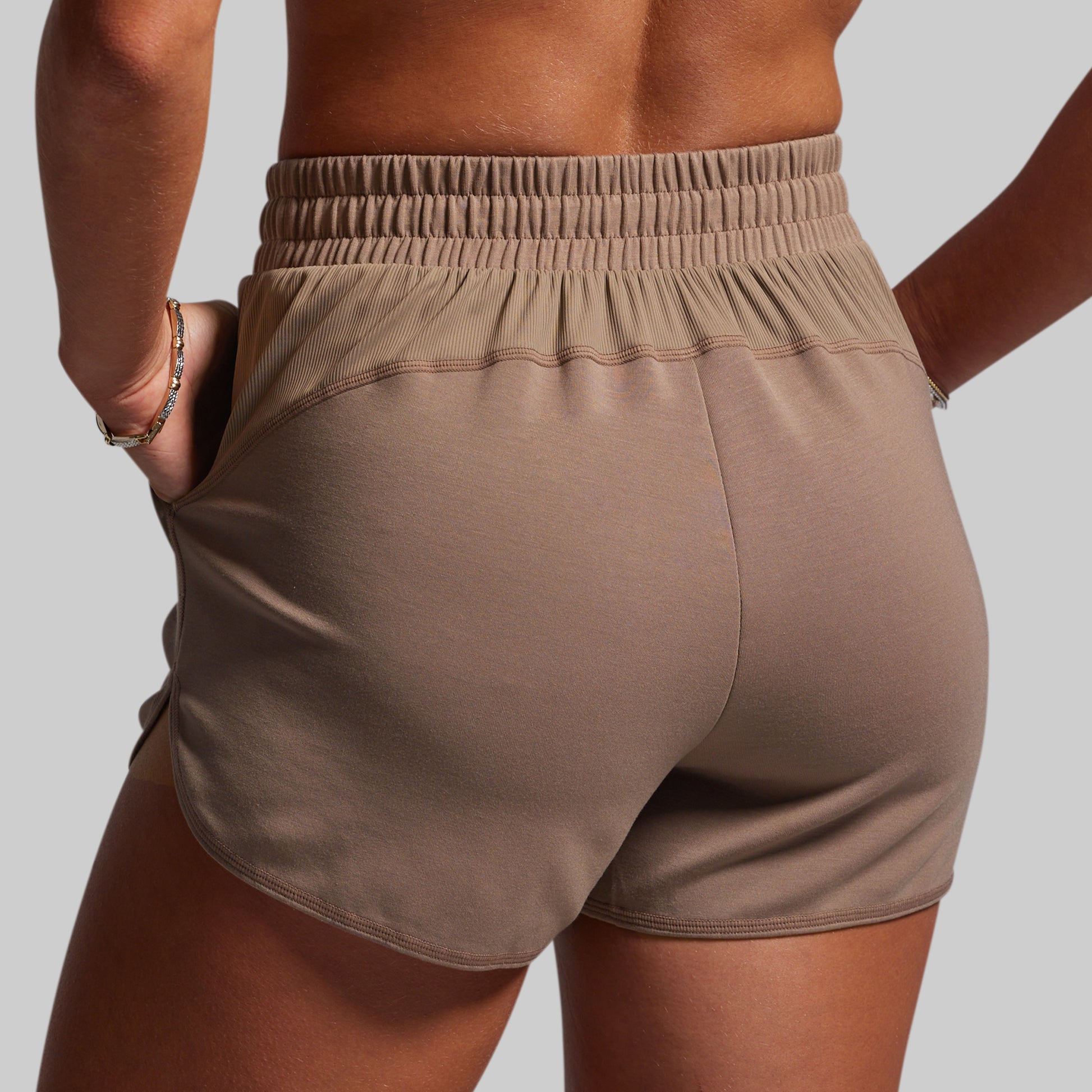 Brown shorts worn by a person on a plain background