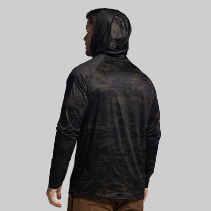 Person wearing a black camouflage hooded sun shirt on a gray background