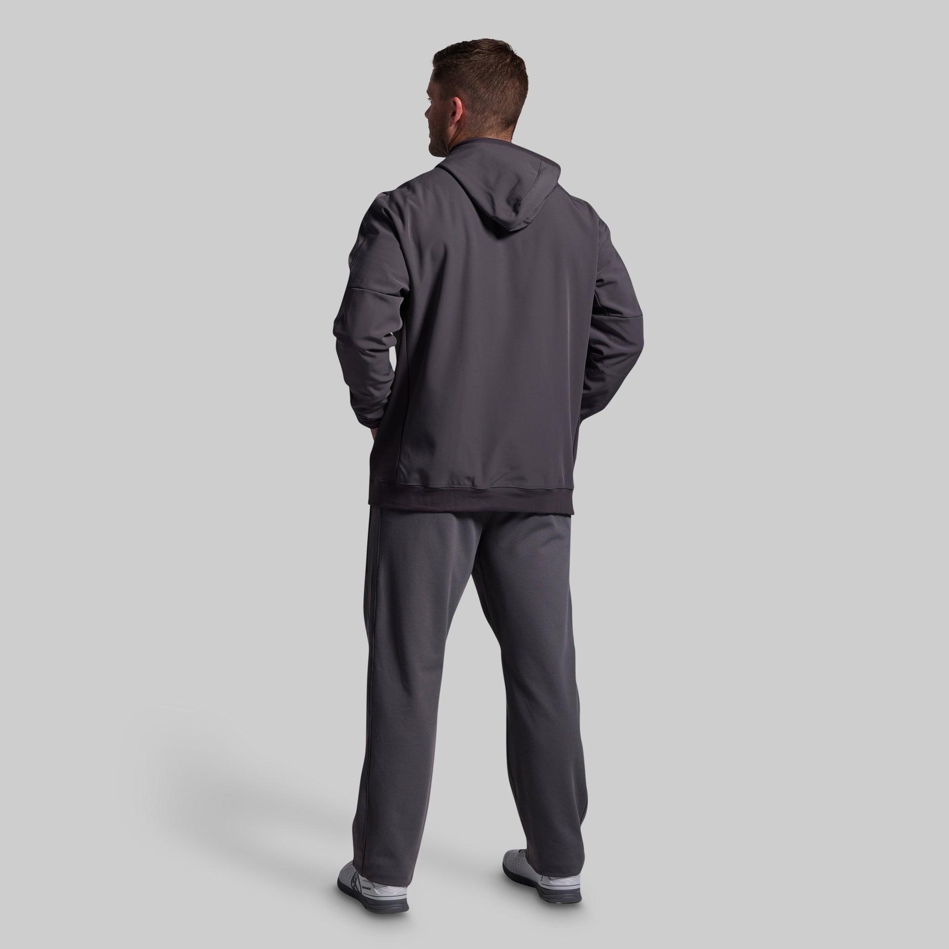 Man wearing a gray tracksuit on a light gray background