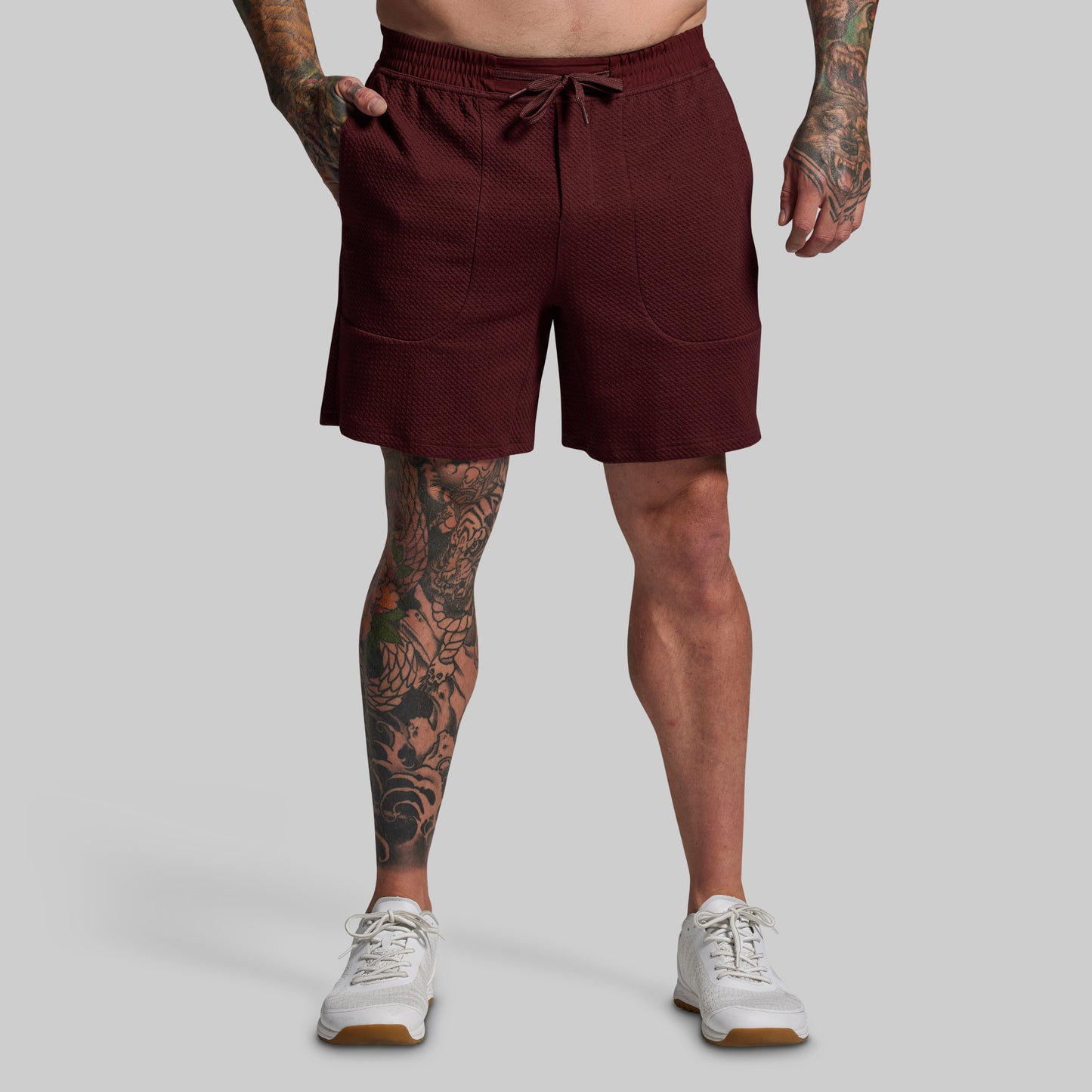 Person wearing maroon shorts on a gray background