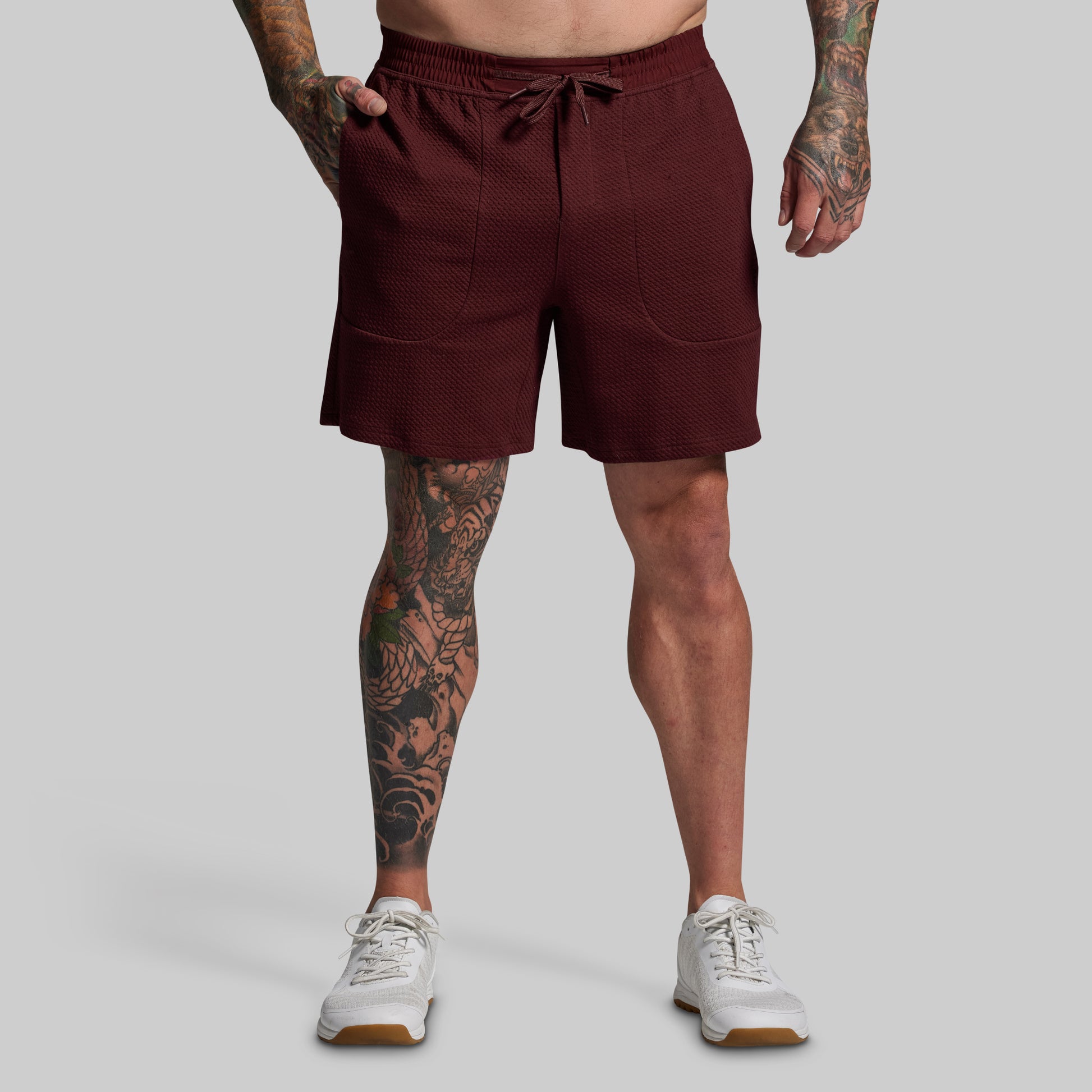 Person wearing maroon shorts on a gray background