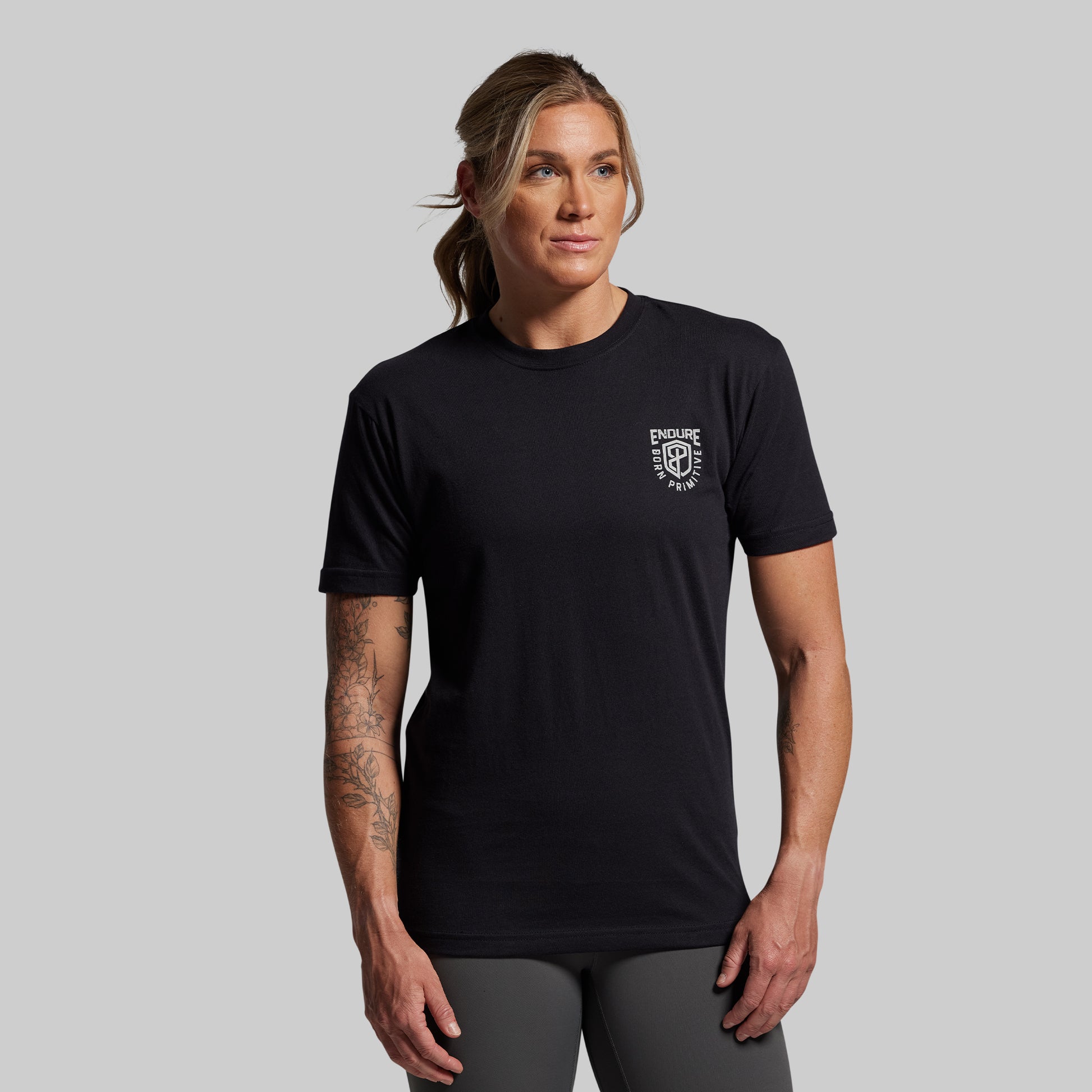 Person wearing a black t-shirt with a logo on a gray background