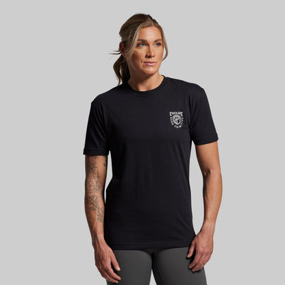 Person wearing a black t-shirt with a logo on a gray background