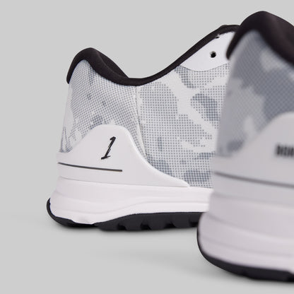 Close-up of a white and black sneaker with a visible brand logo on a light gray background