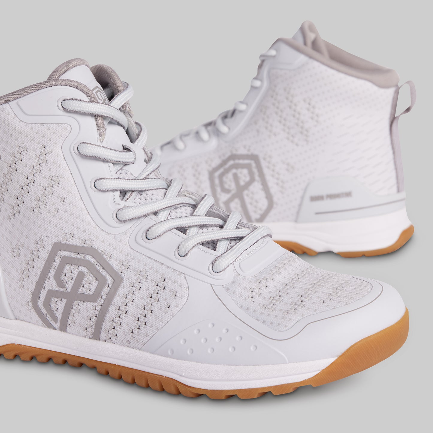 White athletic shoes with brown soles on a light gray background