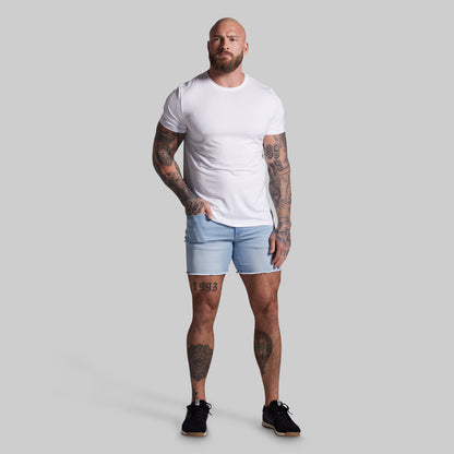 Man wearing a white t-shirt and light blue shorts on a gray background