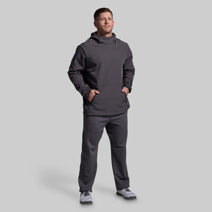 Man wearing a dark gray hoodie and pants on a light gray background