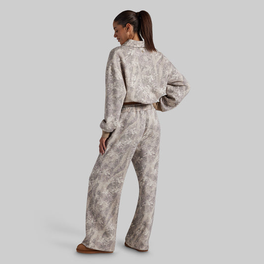 A woman shown from the back wearing a matching cropped long-sleeve top and wide-leg pants set in a light beige and gray abstract pattern.