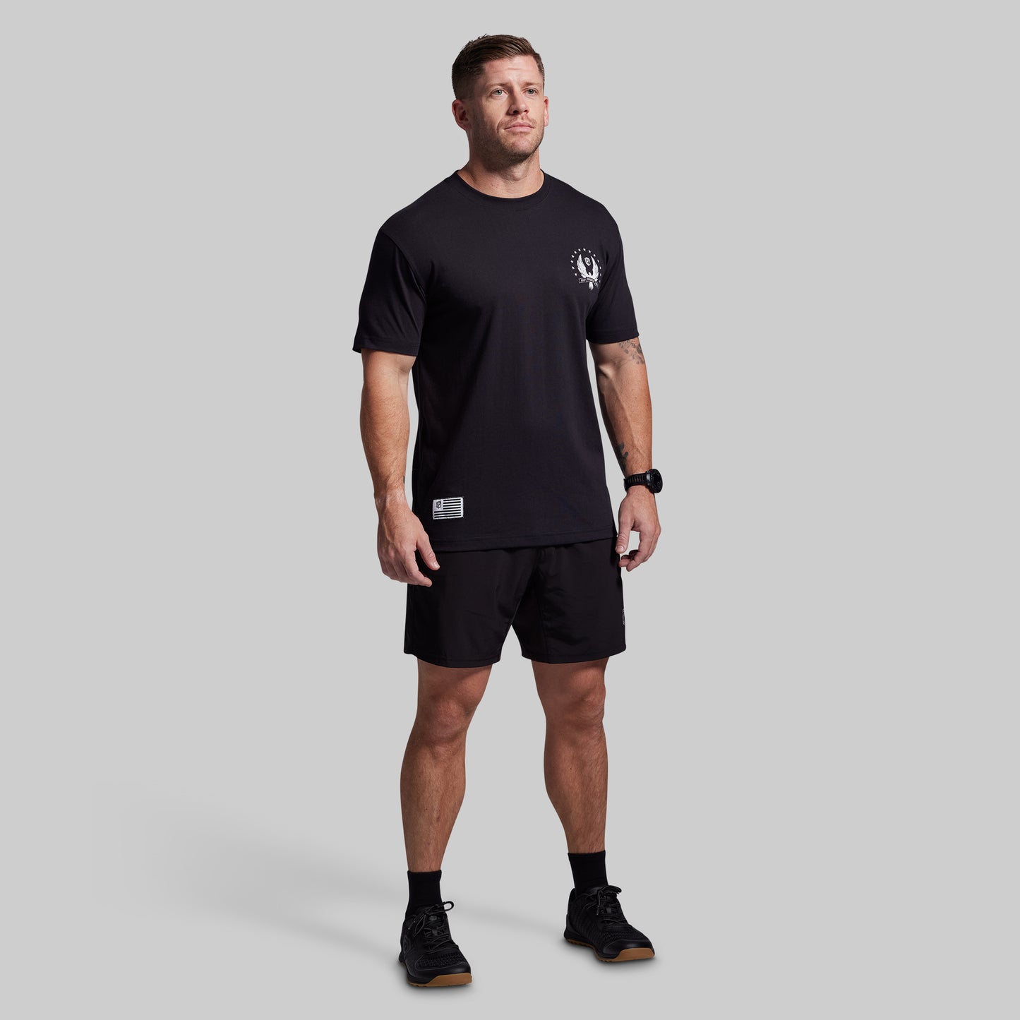 Man wearing a black t-shirt and shorts set on a gray background