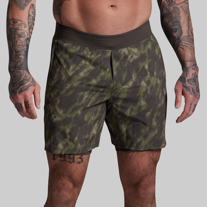 Person wearing green camouflage shorts on a gray background