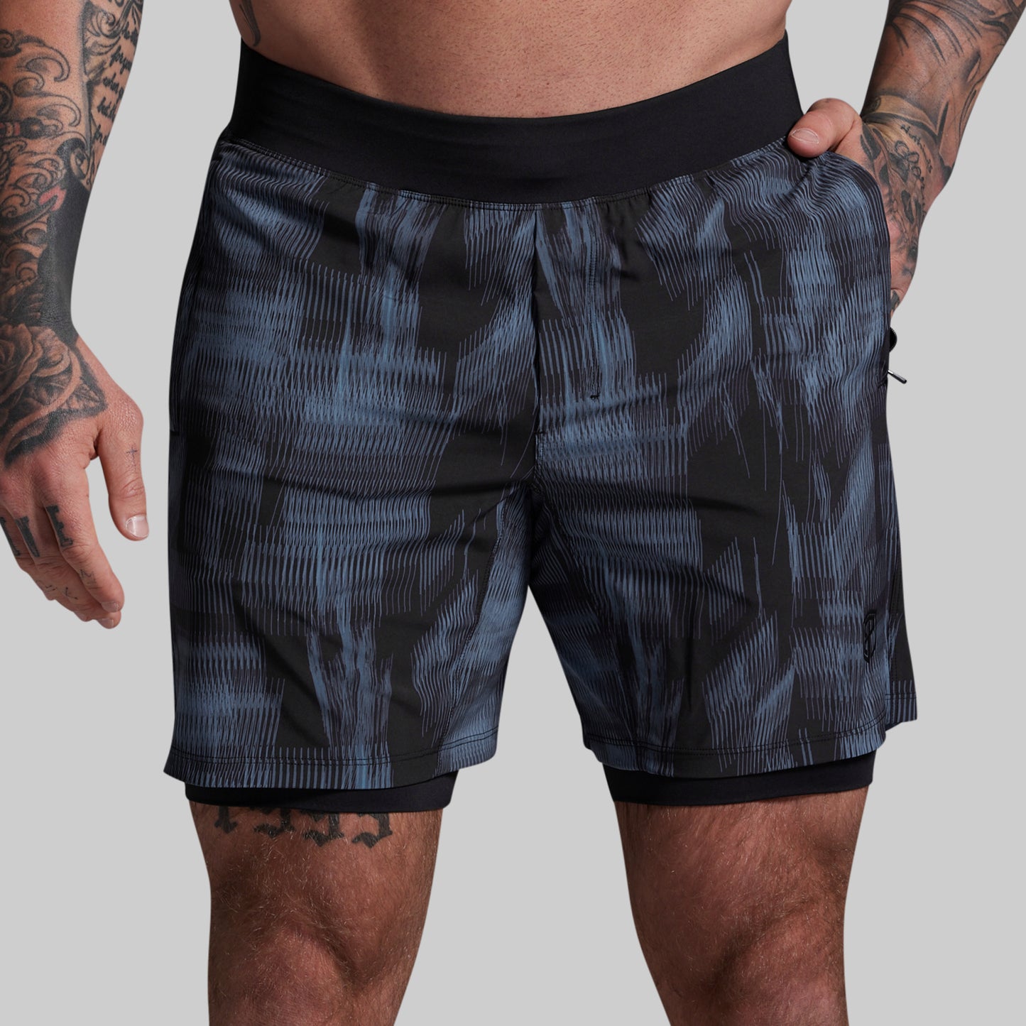 Person wearing black and blue patterned shorts on a gray background