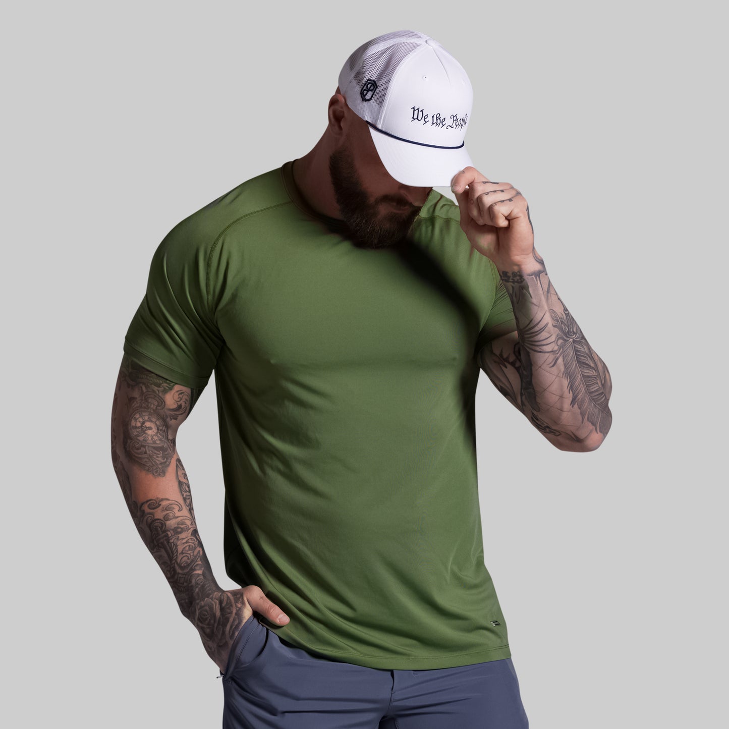 Man wearing a green t-shirt and white cap with text on a gray background