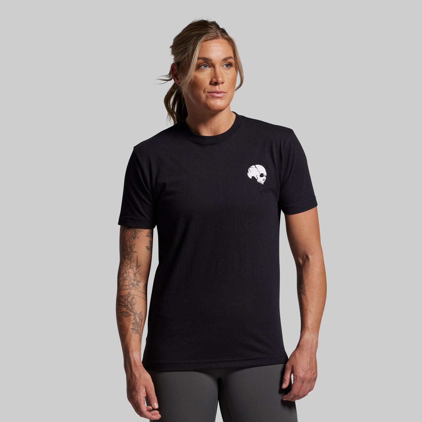 Person wearing a black t-shirt with a logo on a gray background
