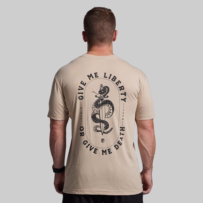 Man wearing a beige t-shirt with a snake and text design on the back against a gray background