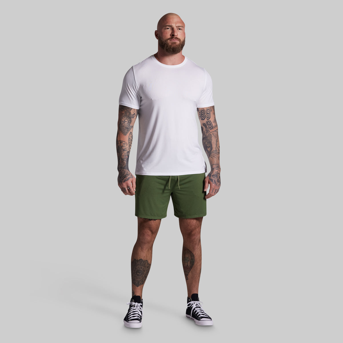 Man wearing a white t-shirt and green shorts on a gray background