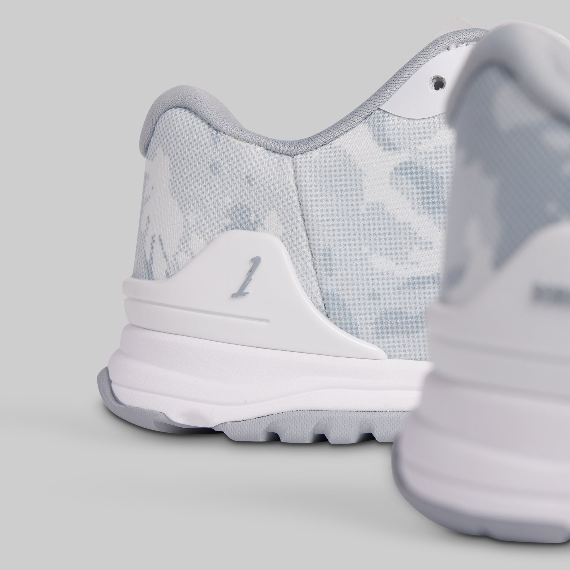 Close-up of a white sneaker with gray accents on a light gray background