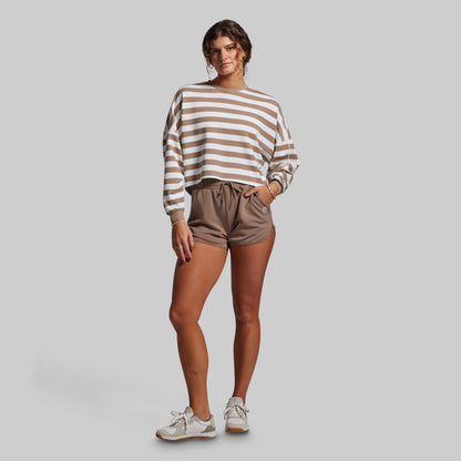 Woman wearing a striped sweater and shorts on a plain background