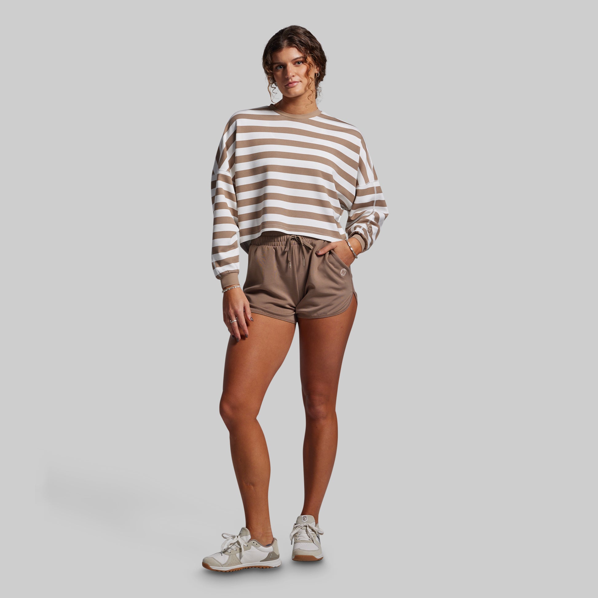 Woman wearing a striped sweater and shorts on a plain background