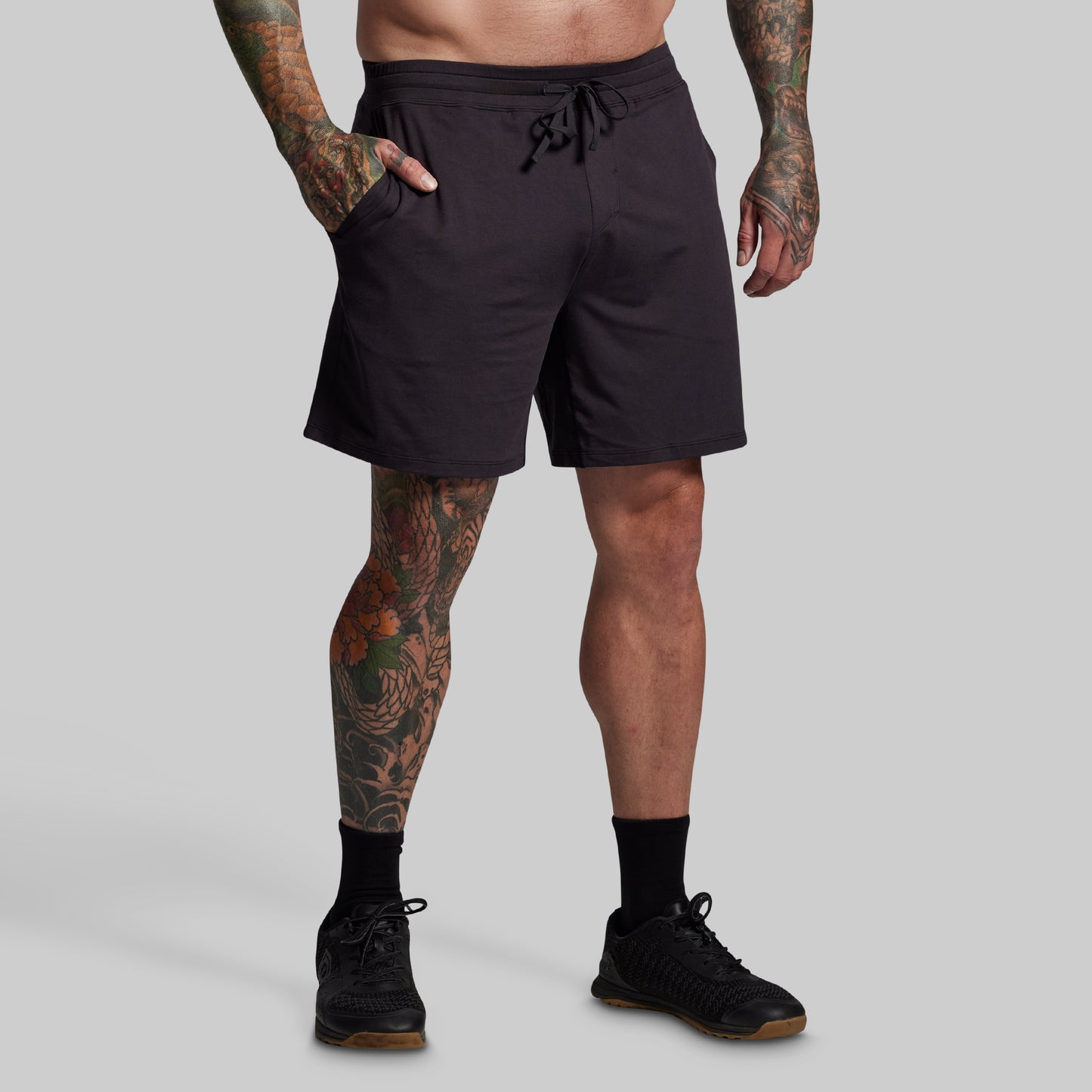 Person wearing black shorts on a gray background