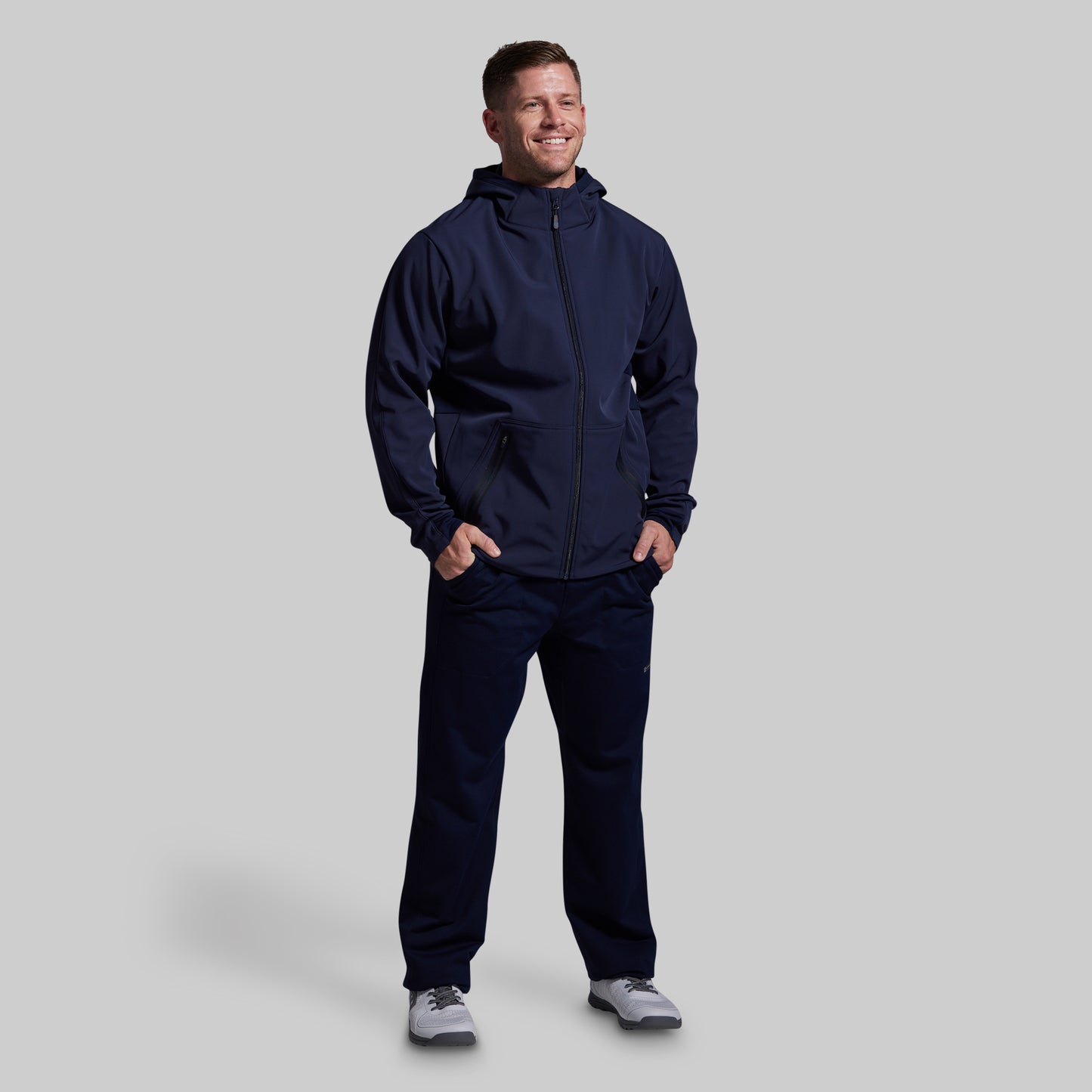 Man wearing a navy blue tracksuit on a light gray background