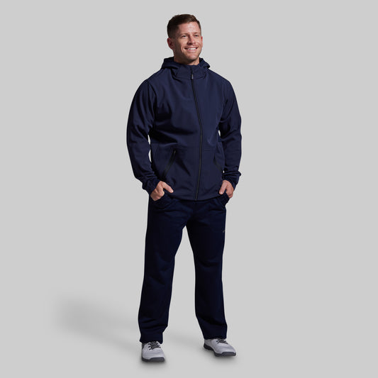 Man wearing a navy blue tracksuit on a light gray background
