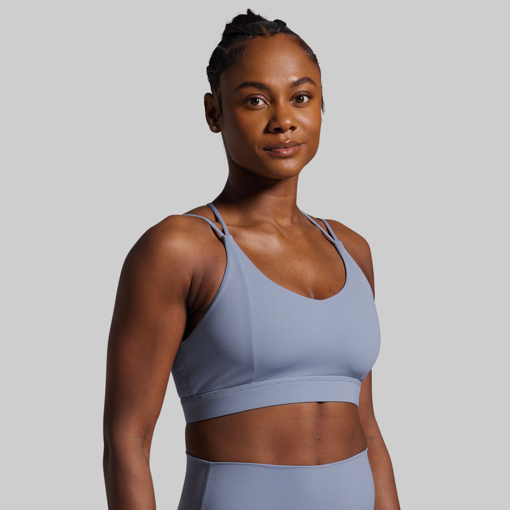 Woman wearing a light blue sports bra and leggings against a gray background
