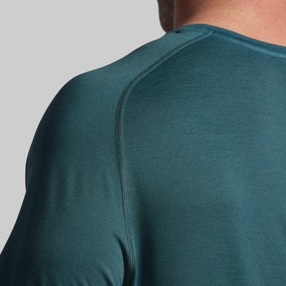 Close-up of a person wearing a teal long-sleeve shirt on a gray background