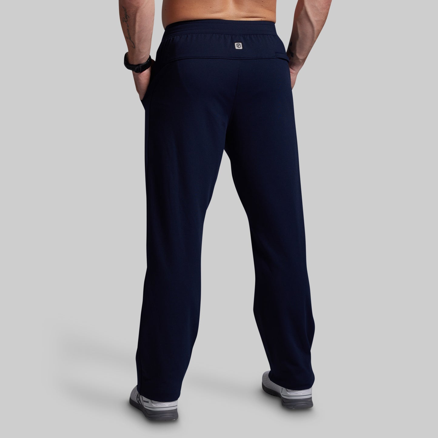 Person wearing navy blue athletic pants on a gray background