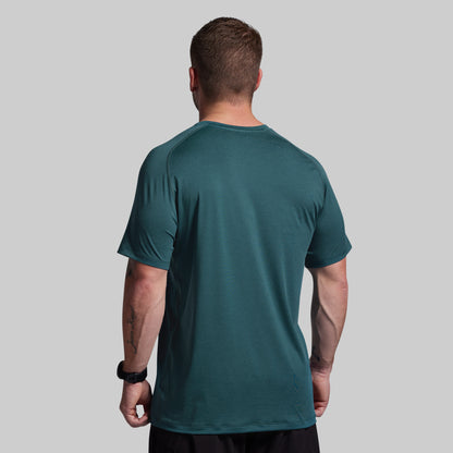 Man wearing a teal t-shirt on a gray background