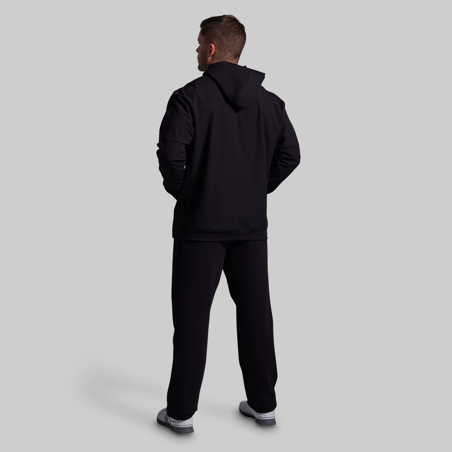 Person wearing a black tracksuit on a light gray background