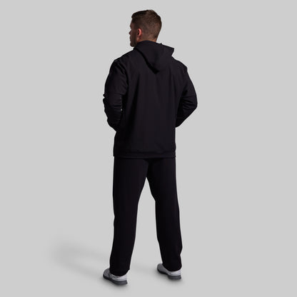 Person wearing a black tracksuit on a light gray background