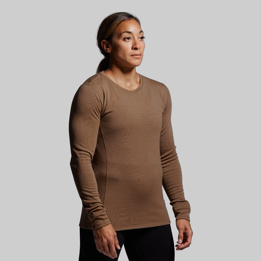 Person wearing a brown long-sleeve shirt against a gray background