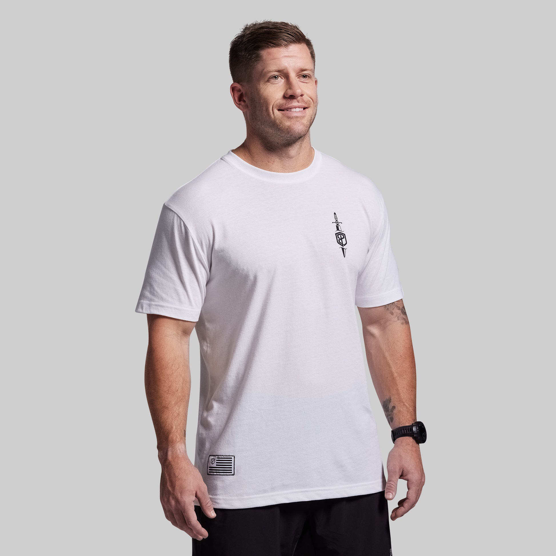 Man wearing a white t-shirt with a small logo on a gray background
