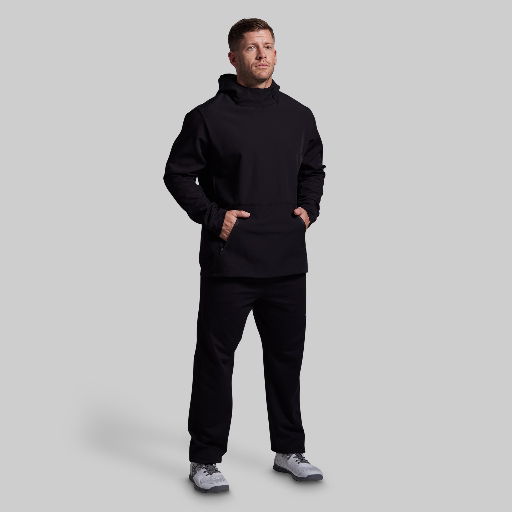 Man wearing a black hoodie and pants on a light gray background