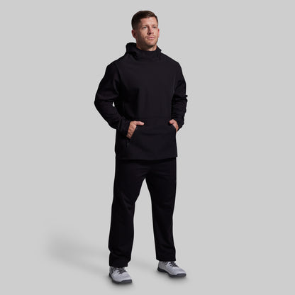 Man wearing a black hoodie and pants on a light gray background
