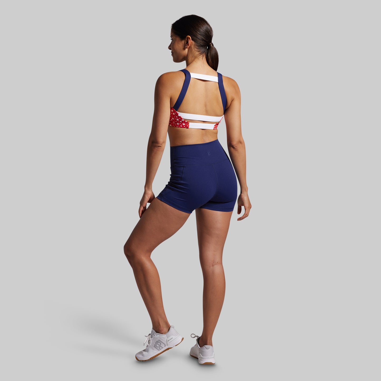 Woman wearing a sports bra and shorts with an American flag design on a gray background