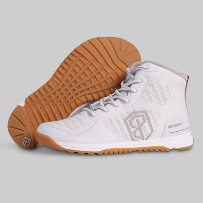 White athletic shoe with brown sole on a gray background