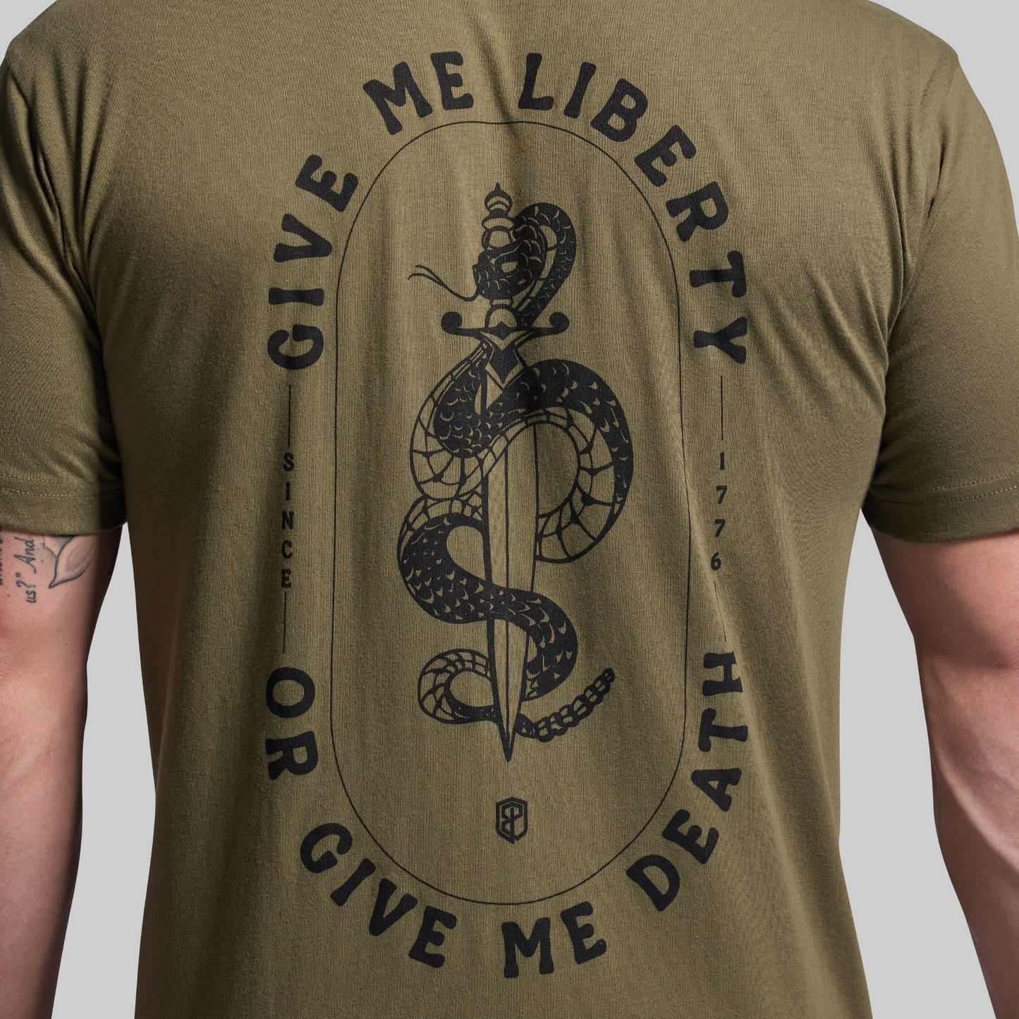 Green t-shirt with black snake and sword graphic and text on a plain background