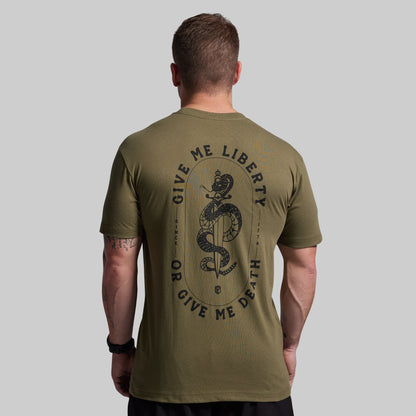 Man wearing an olive green t-shirt with a snake and text design on the back, on a gray background.
