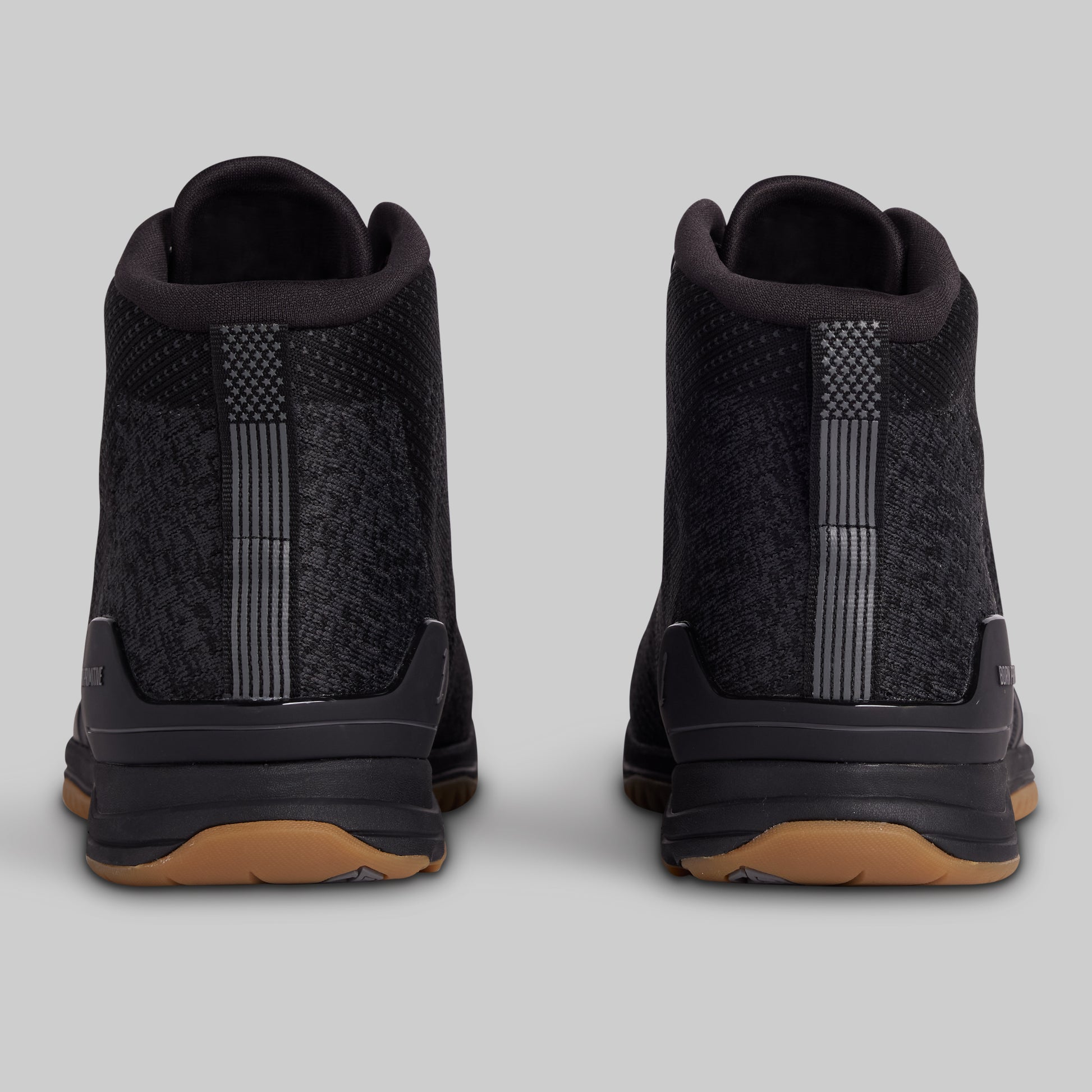 Black high-top sneakers with brown soles on a gray background